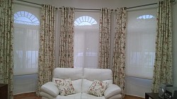 Floral eyelet curtains with cream vision blinds.